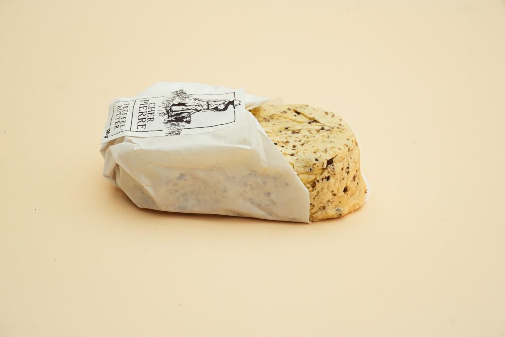 Trüffelbutter aus der Holzform mit sichtbaren Trüffelstückchen